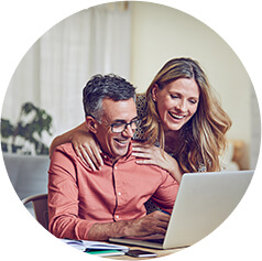 A couple smiling as they at the computer