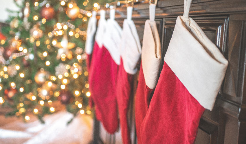 Closeup of red holiday stockings hanging on a brown mantle near a Christmas tree