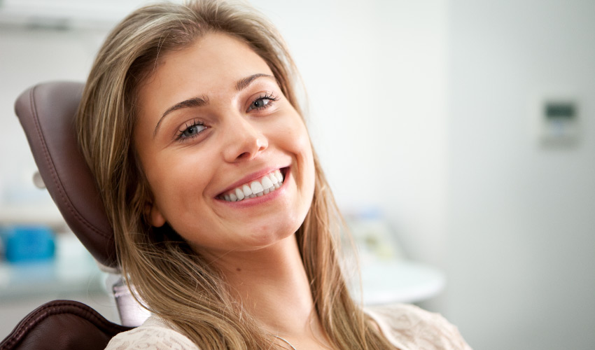 Brunette woman in a dental chair smiles after receiving an oral cancer screening at True Dental in Odenton, MD