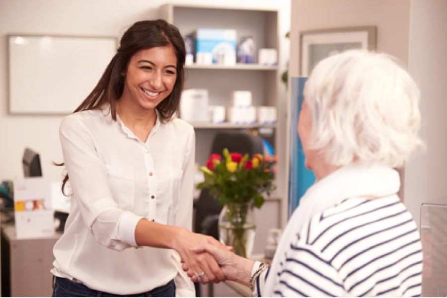 receptionist warmly greets a senior patient at the family dentist office