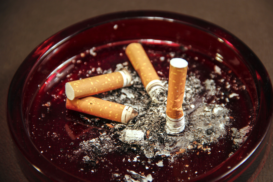Several cigarette butts in a red-colored ashtray