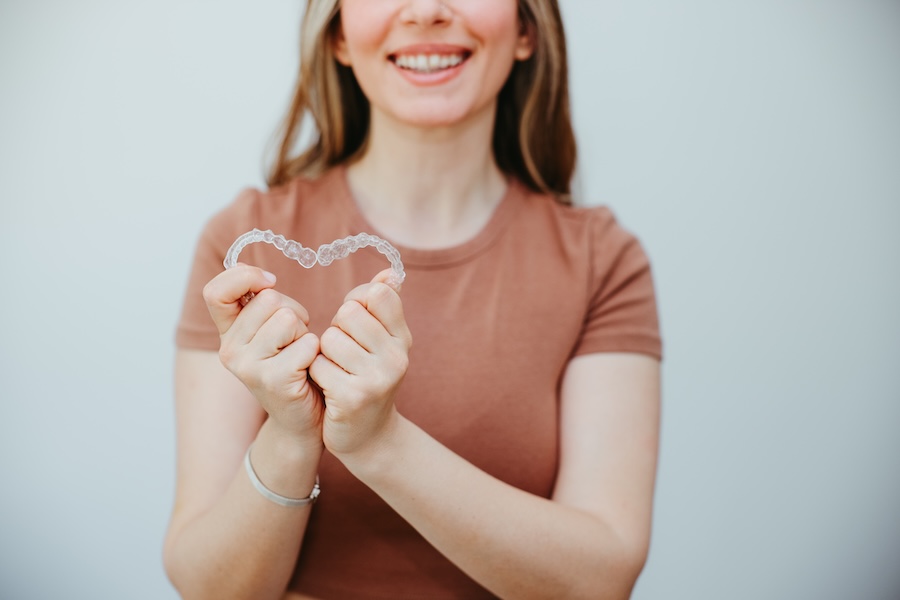 woman holding clear aligner trays in a heart shape during clear aligner therapy